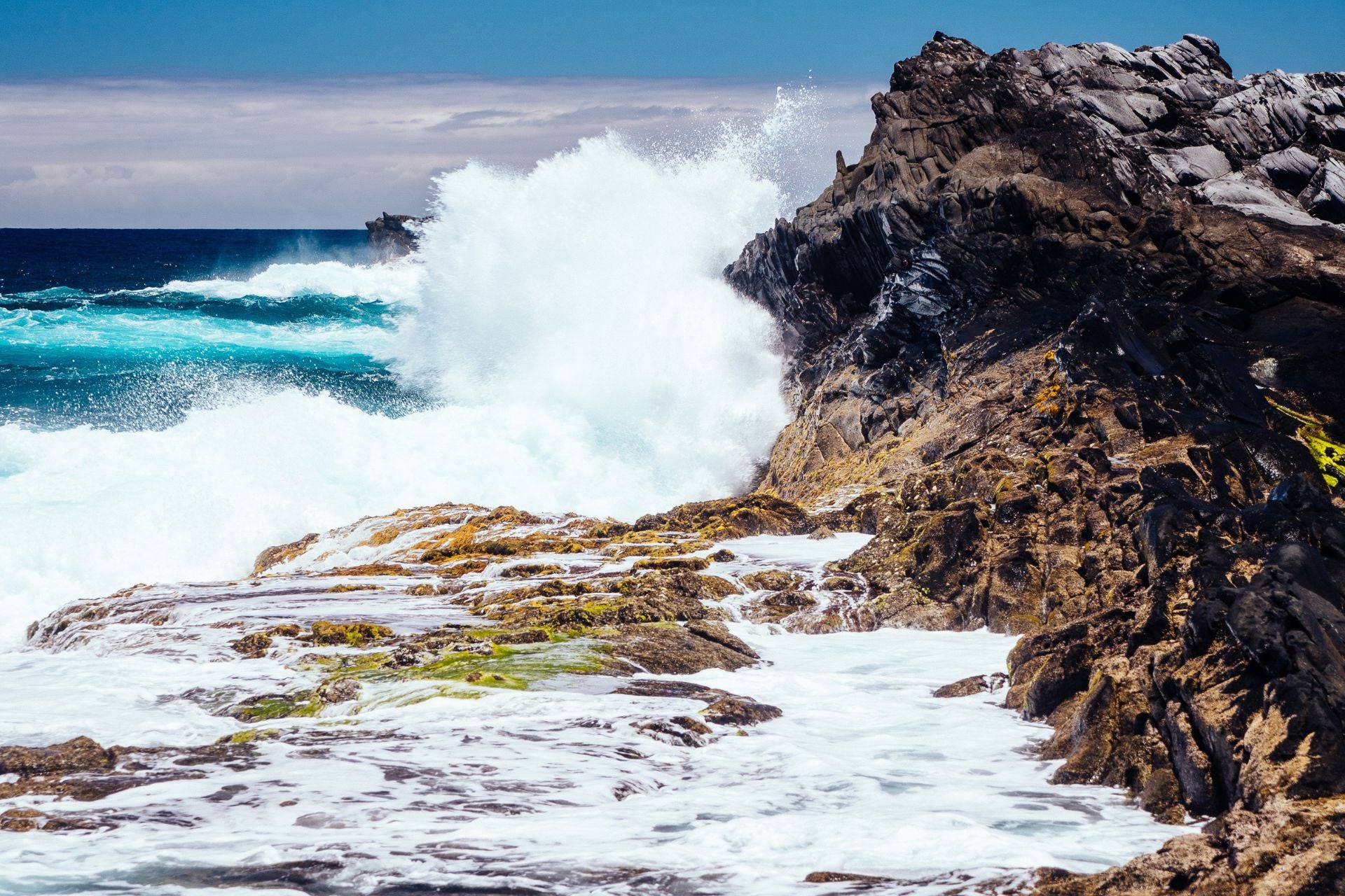 Hoge golven spatten uiteen op bruine rotsen op Gran Canaria