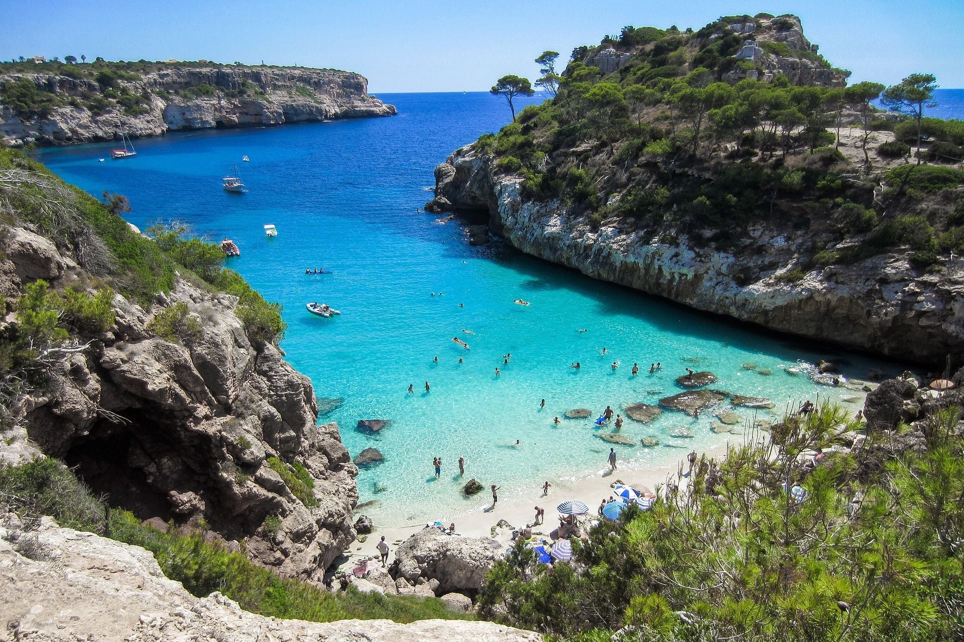 Helder blauwgroen water tussen rotsformaties met een klein strandje op Mallorca