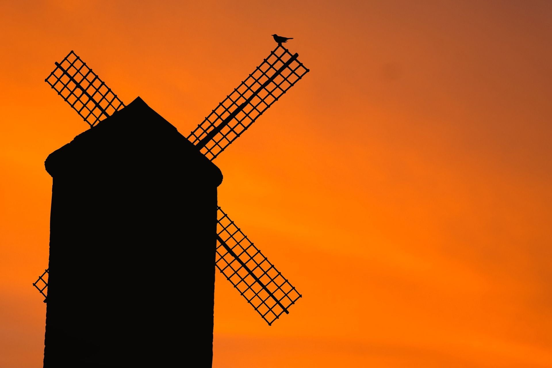 Oude molen bij oranje hemel bij zonsondergang
