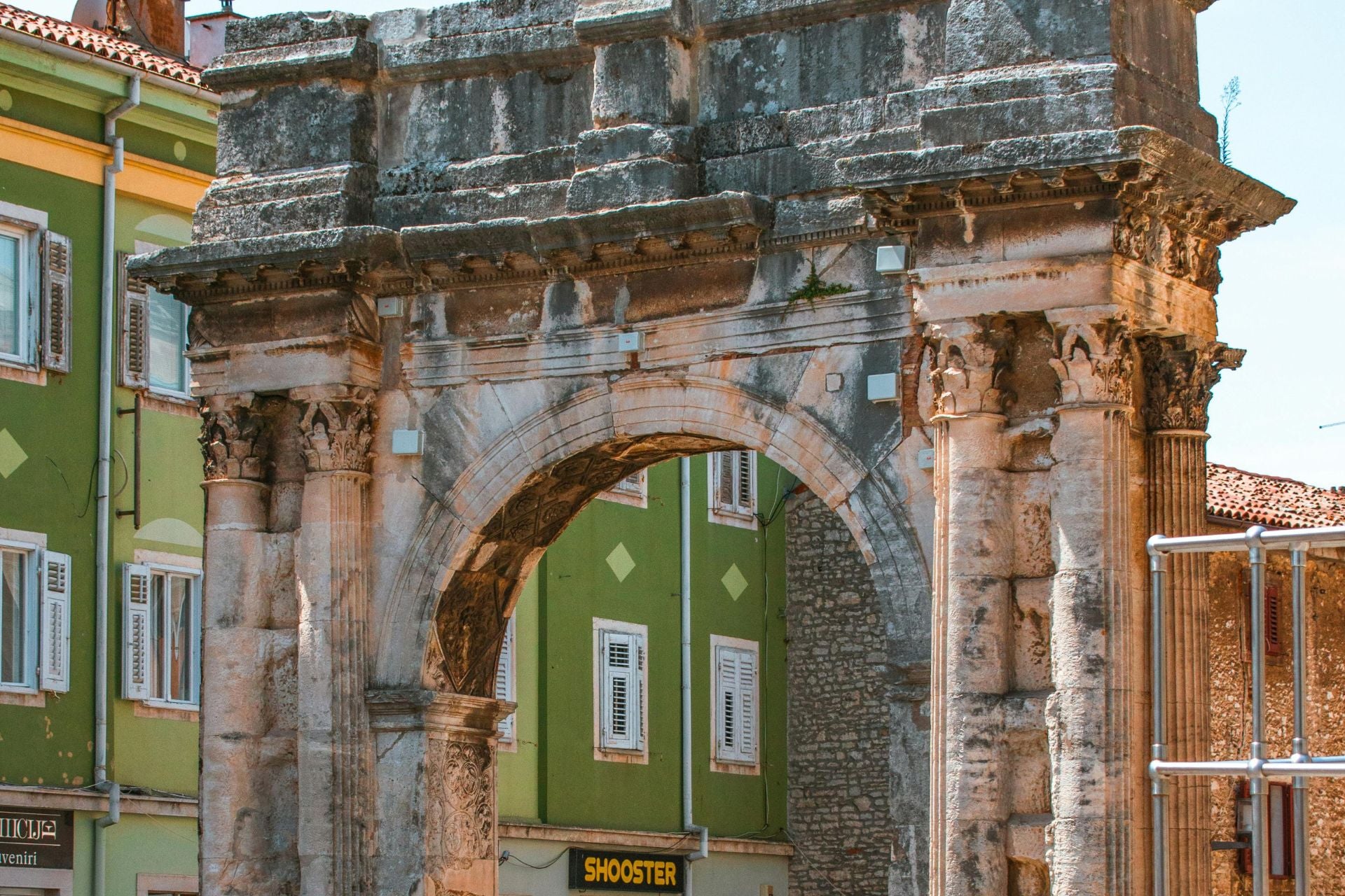 Romeinse boog in Pula, Kroatië met groene huizen op de achtergrond