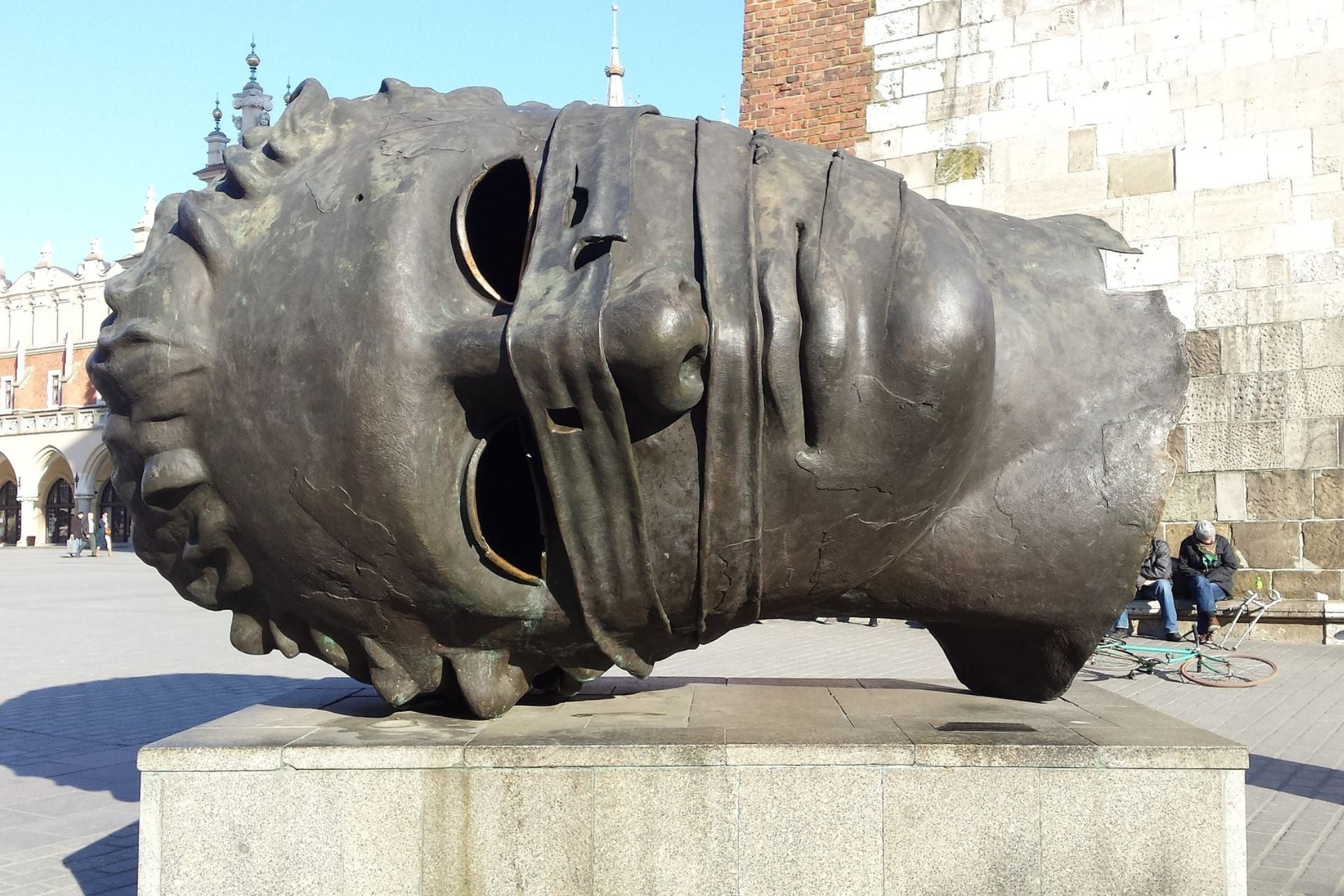 Bronzen beel van liggend hoofd op Grote Markt Krakau