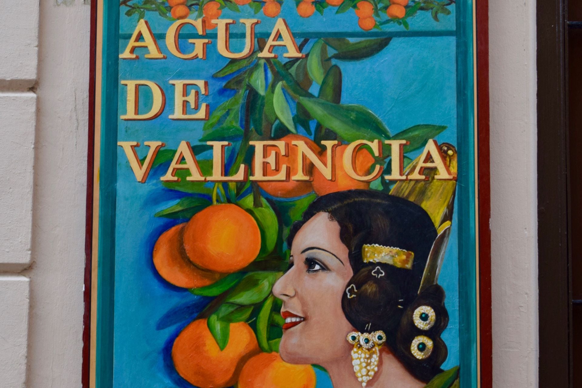 Klassiek reclamebord voor Agua de Valencia met een vrouw en sinaasappelen